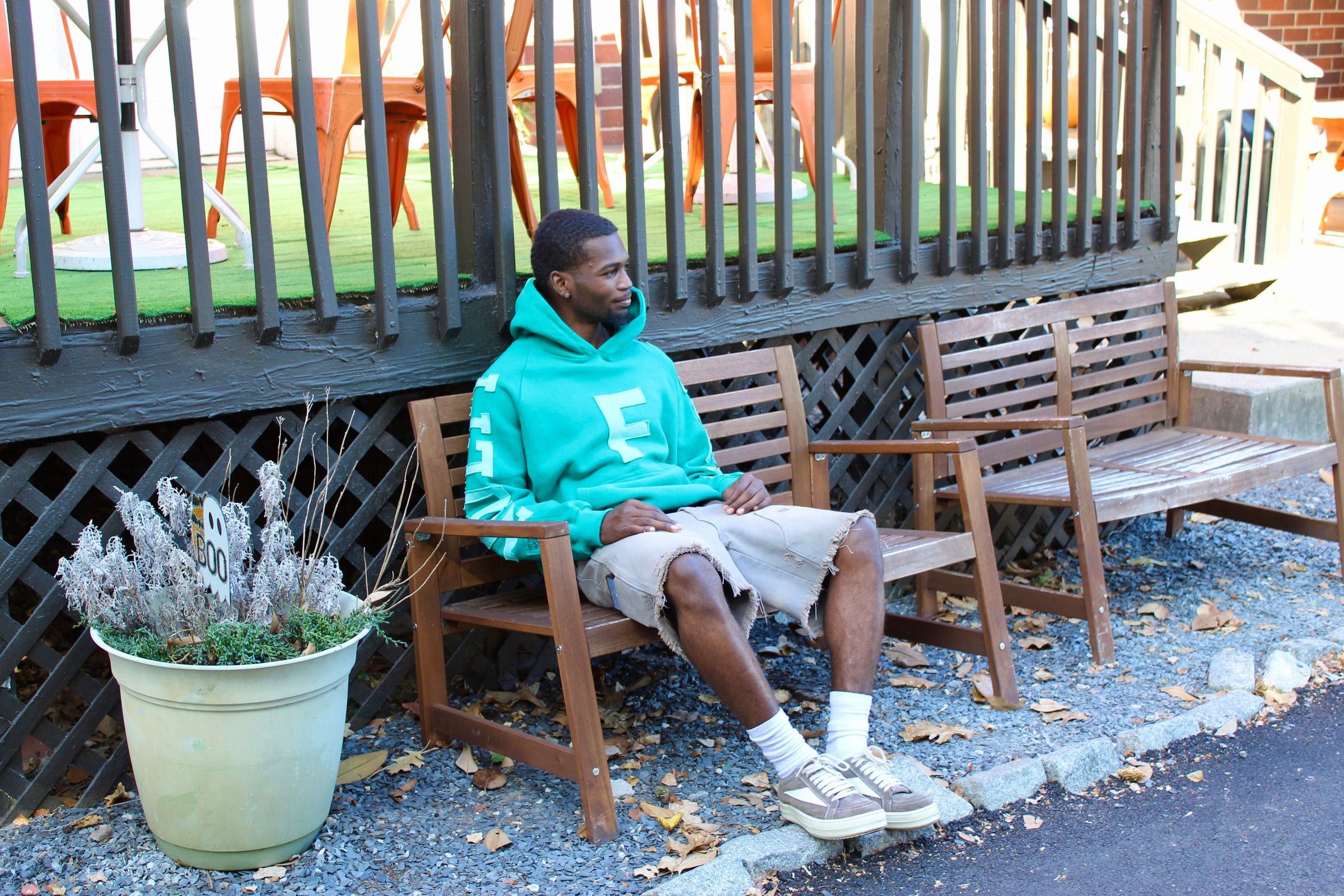 Man sitting on bench wearing a green 1ubu oversized hoodie