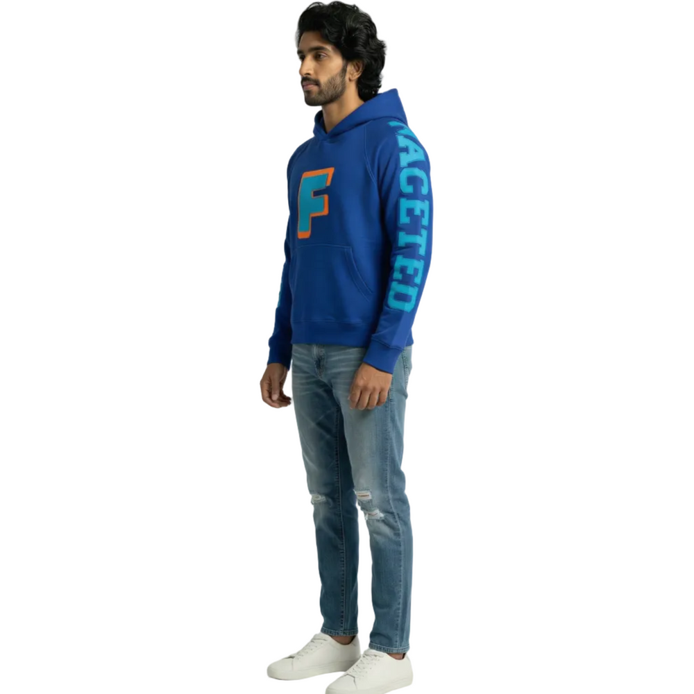 Person wearing a blue oversized hoodie with a logo and text, standing against a white background