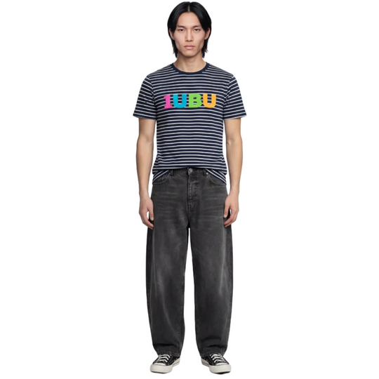 Person wearing a striped shirt with colorful text and dark jeans on a white background