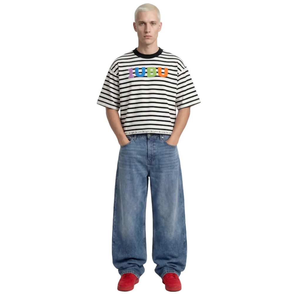 Person wearing a striped shirt with colorful text, blue jeans, and red shoes on a white background